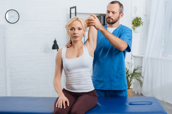portrait of chiropractor stretching womans arm on massage table