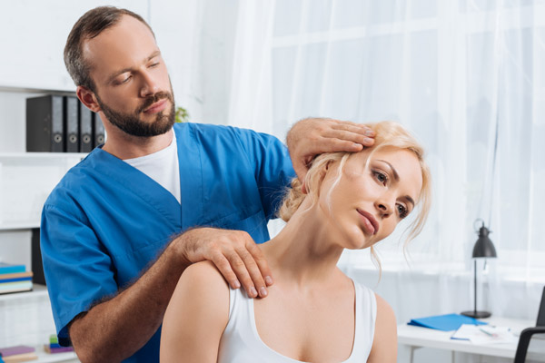 portrait of chiropractor stretching neck of woman during appoint